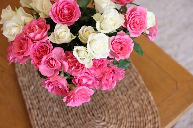 Photo of Vase with beautiful bouquet of roses on wooden table indoors, above view. Space for text