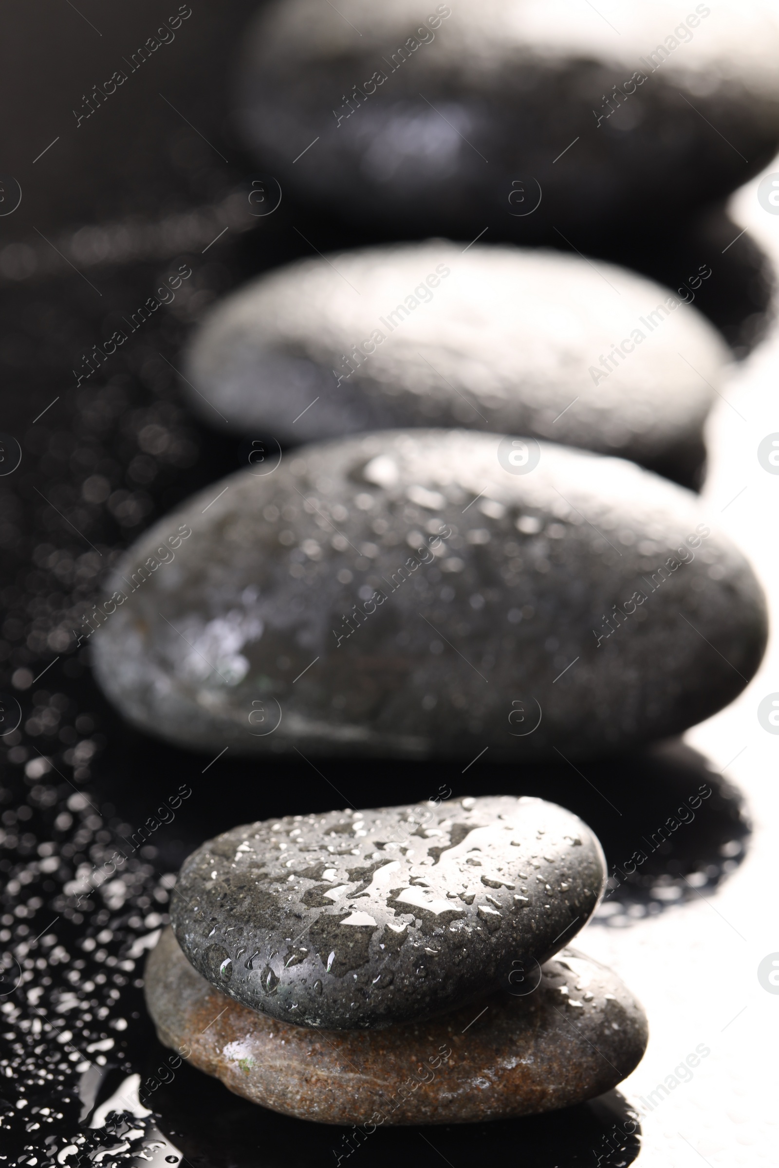 Photo of Grey spa stones with water drops on black background, closeup