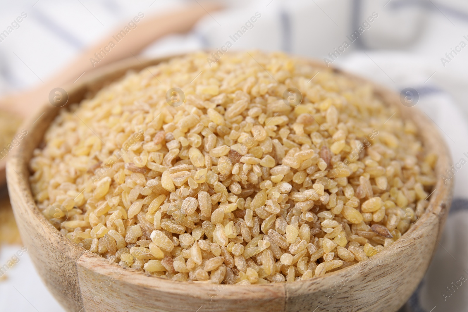 Photo of Raw bulgur in bowl on table, closeup