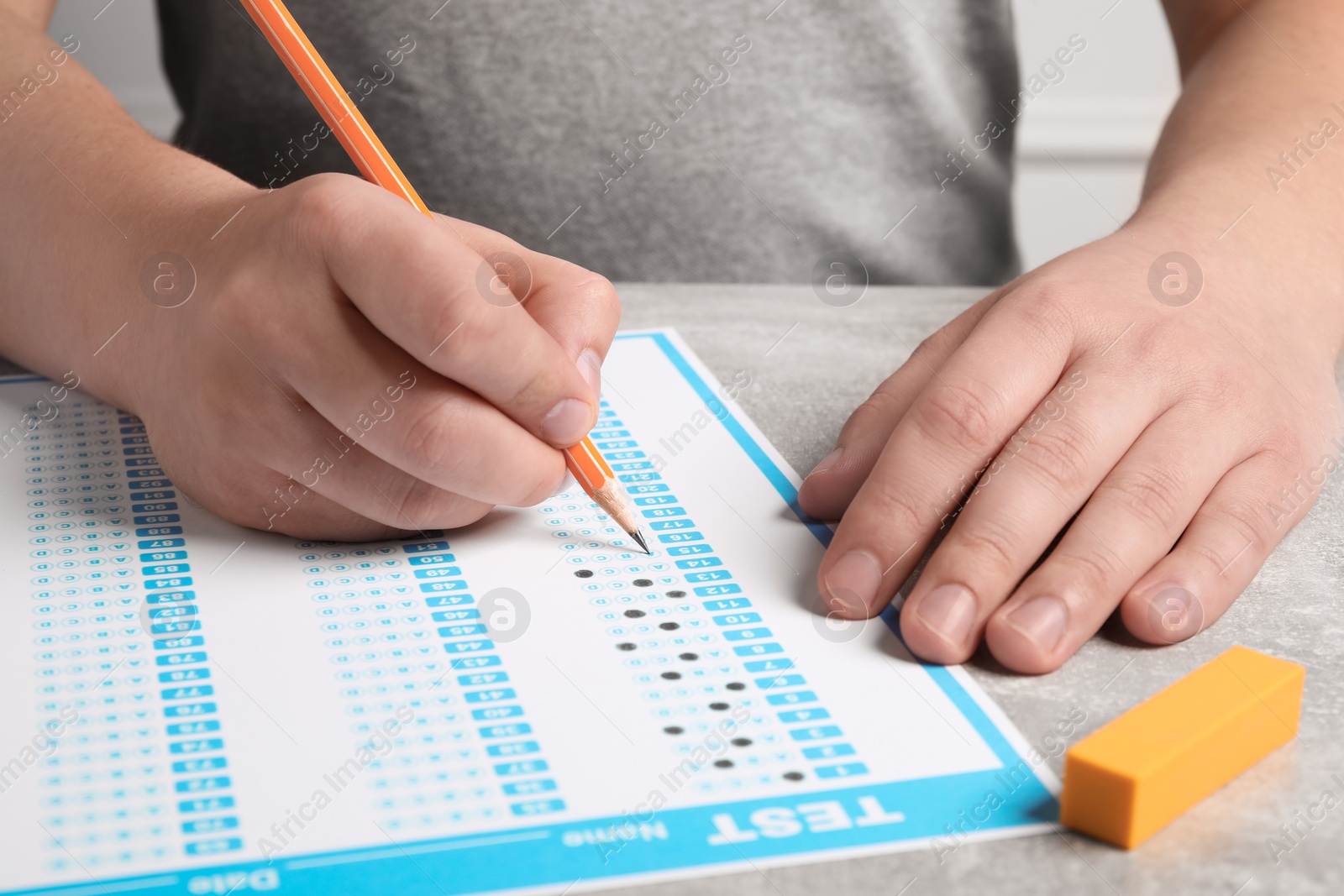 Photo of Student filling answer sheet at table, closeup. Passing exam