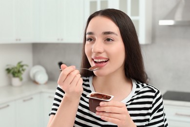 Photo of Happy woman eating tasty yogurt in kitchen
