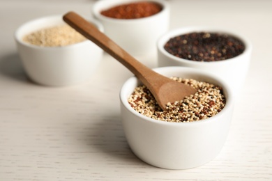 Spoon and bowl with mixed quinoa seeds on table. Space for text