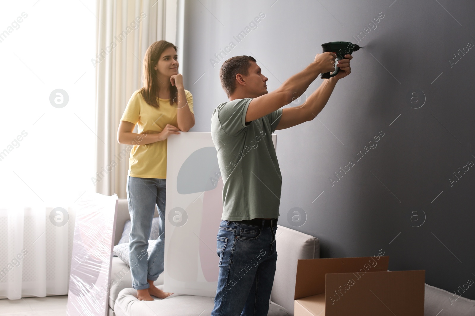 Photo of Couple decorating room with pictures together. Interior design