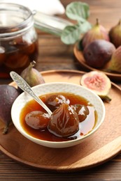 Photo of Bowl of tasty sweet fig jam on wooden table