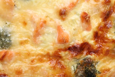 Photo of Delicious homemade quiche with salmon and broccoli as background, top view