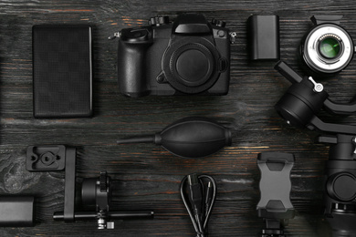 Flat lay composition with camera and video production equipment on black wooden table