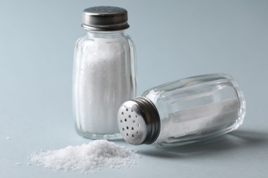 Photo of Natural salt in shakers on color background