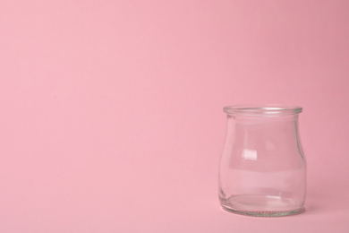 Photo of Open empty glass jar on pink background, space for text