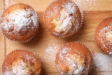 Delicious sweet muffins on wooden board, flat lay