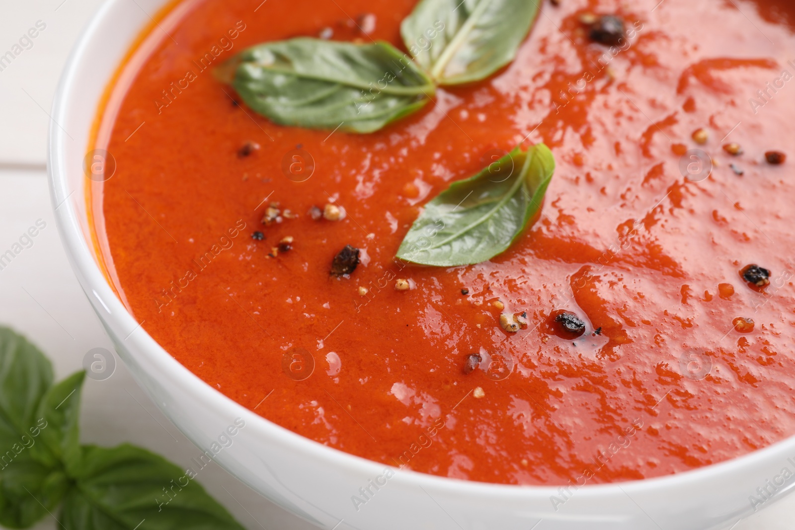 Photo of Delicious tomato cream soup in bowl on white table, closeup