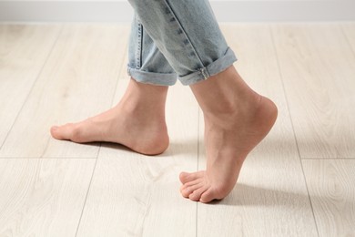 Photo of Woman stepping barefoot in room at home, closeup. Floor heating