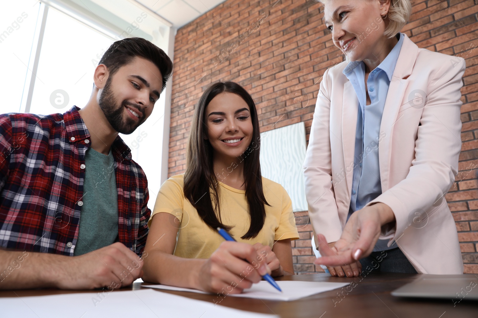 Photo of Female notary working with young couple in office