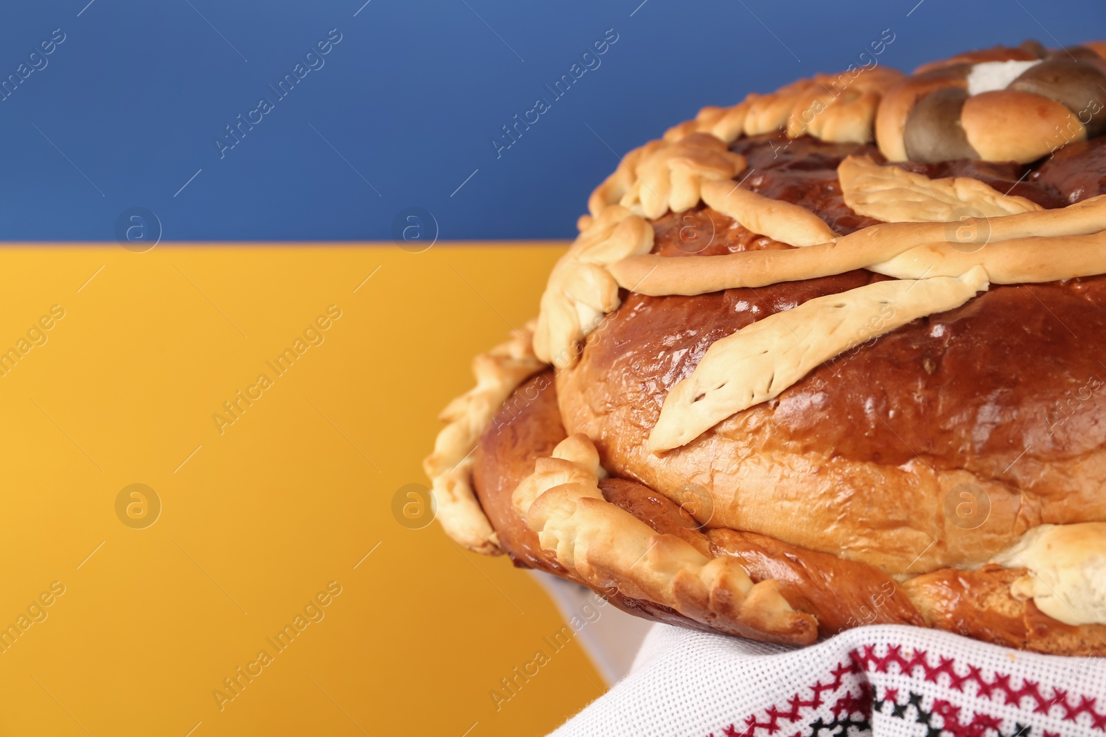 Photo of Korovai with rushnyk on color background, space for text. Ukrainian bread and salt welcoming tradition