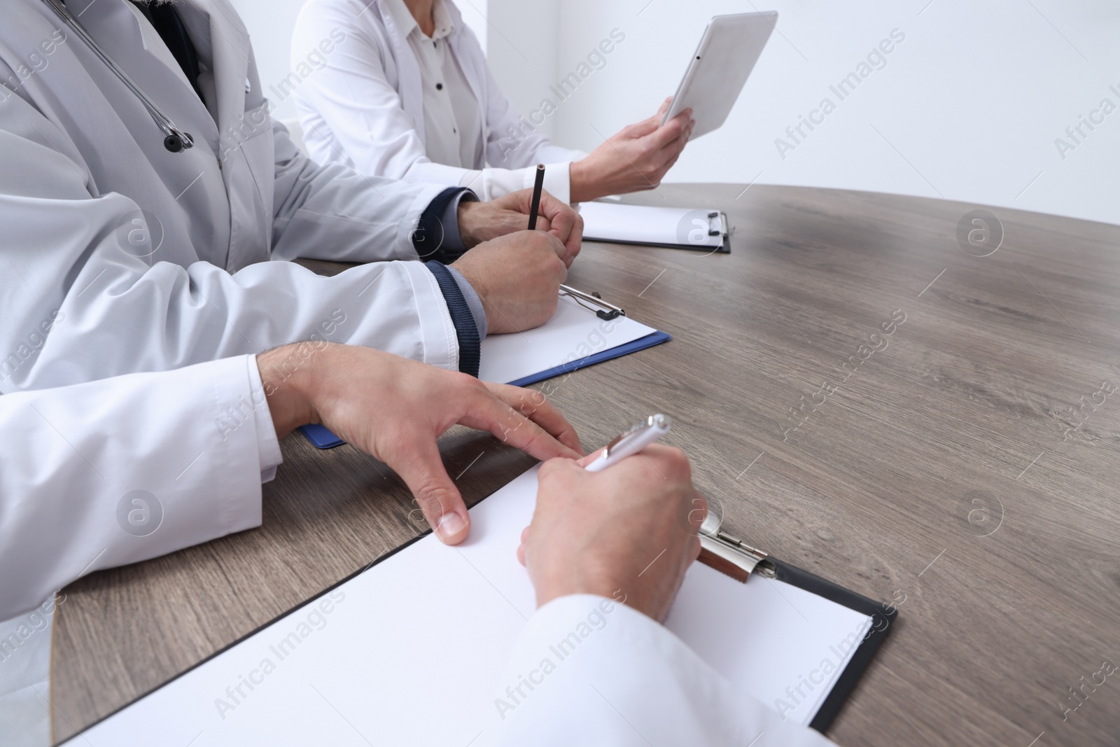 Photo of Doctors working at wooden table in clinic, closeup