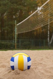 Colorful volleyball ball on sand court, space for text