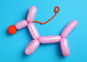 Photo of Dog figure made of modelling balloon on light blue background, top view