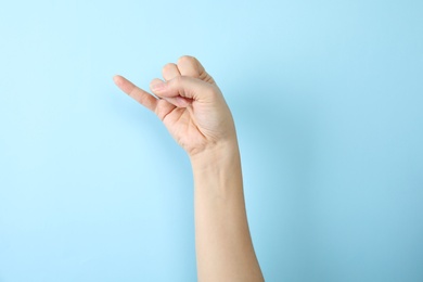 Woman showing J letter on color background, closeup. Sign language