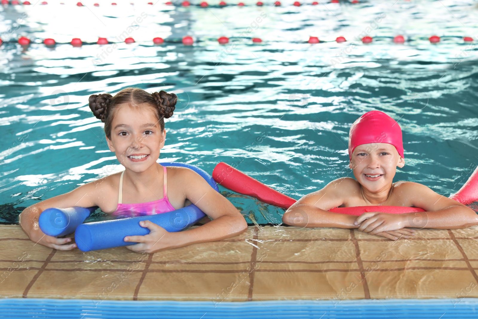 Photo of Little kids with swimming noodles in indoor pool