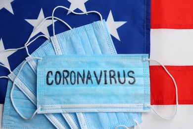 Photo of Medical masks on American flag, flat lay. Coronavirus pandemic in USA