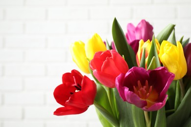 Photo of Beautiful spring tulips near white brick wall, closeup