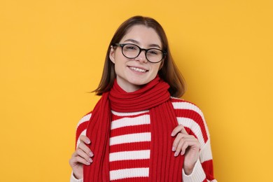 Beautiful woman in warm scarf and glasses on yellow background