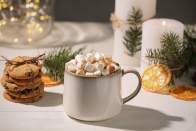 Photo of Cup of hot drink with marshmallows and cookies on white table