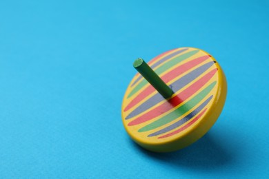 One colorful spinning top on light blue background, closeup. Space for text