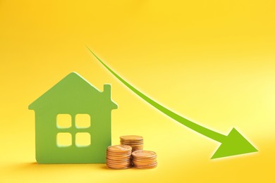 Image of Mortgage concept. House model and coins on yellow background 