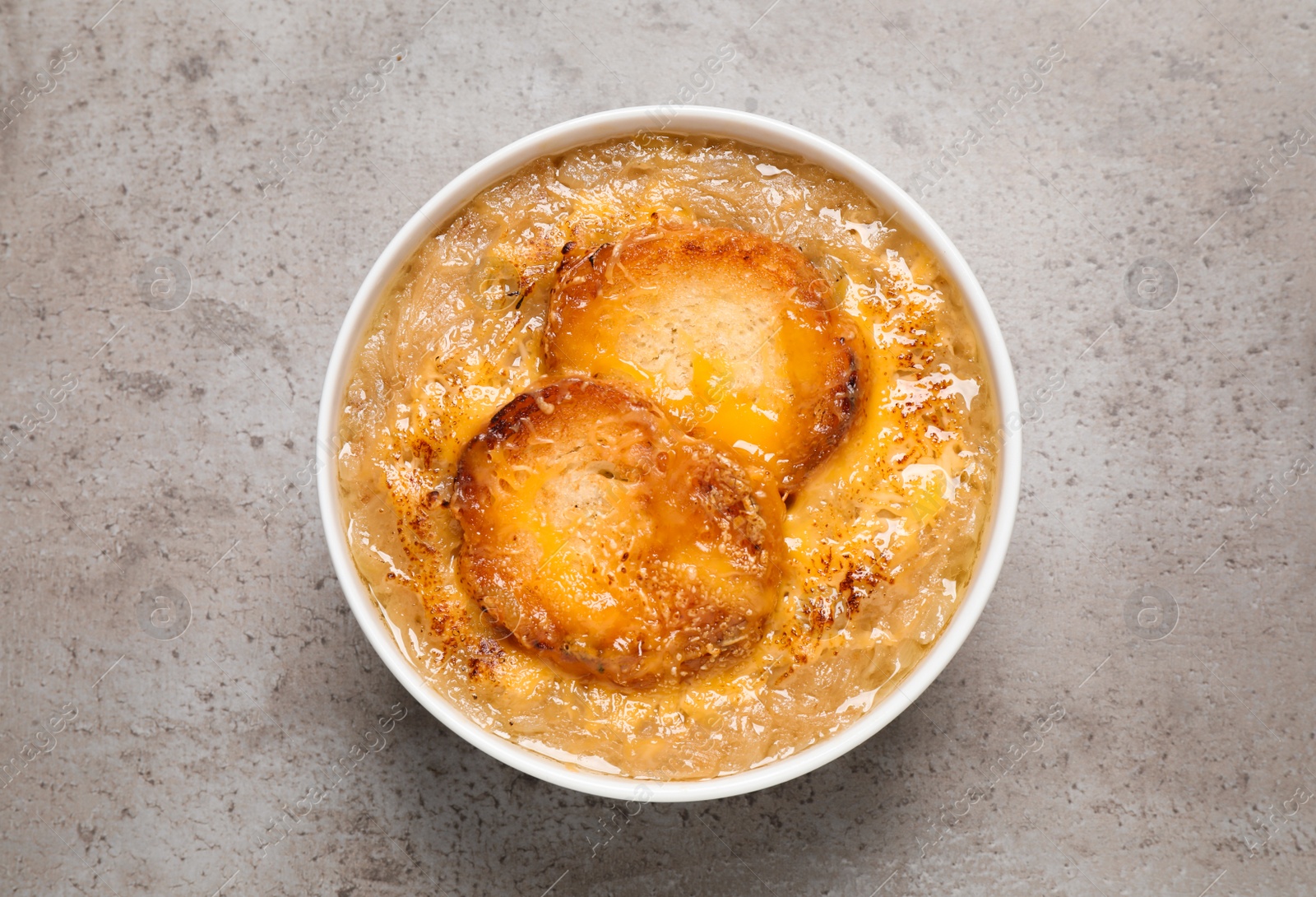 Photo of Tasty homemade french onion soup on grey table, top view