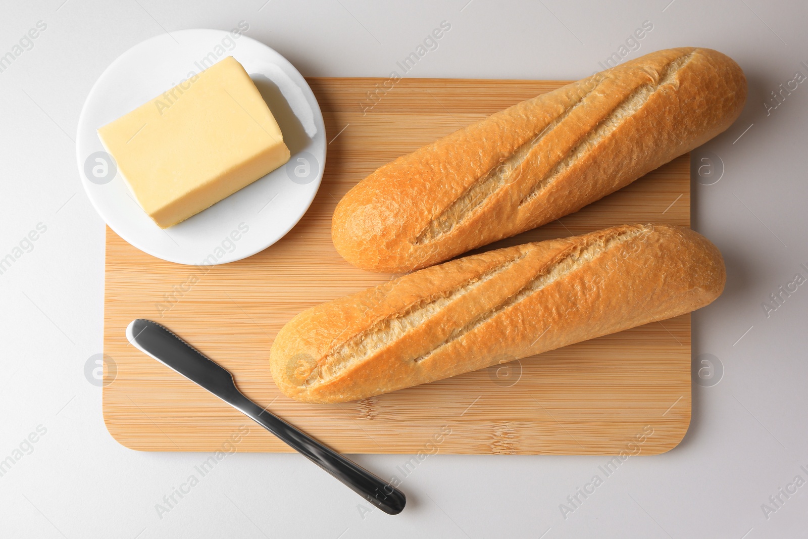 Photo of Tasty baguettes with fresh butter on white table, top view