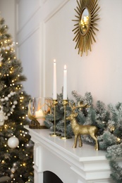 Burning candles on mantelpiece in decorated room. Christmas celebration