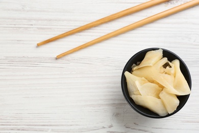 Photo of Spicy pickled ginger and chopsticks on white wooden table, flat lay. Space for text