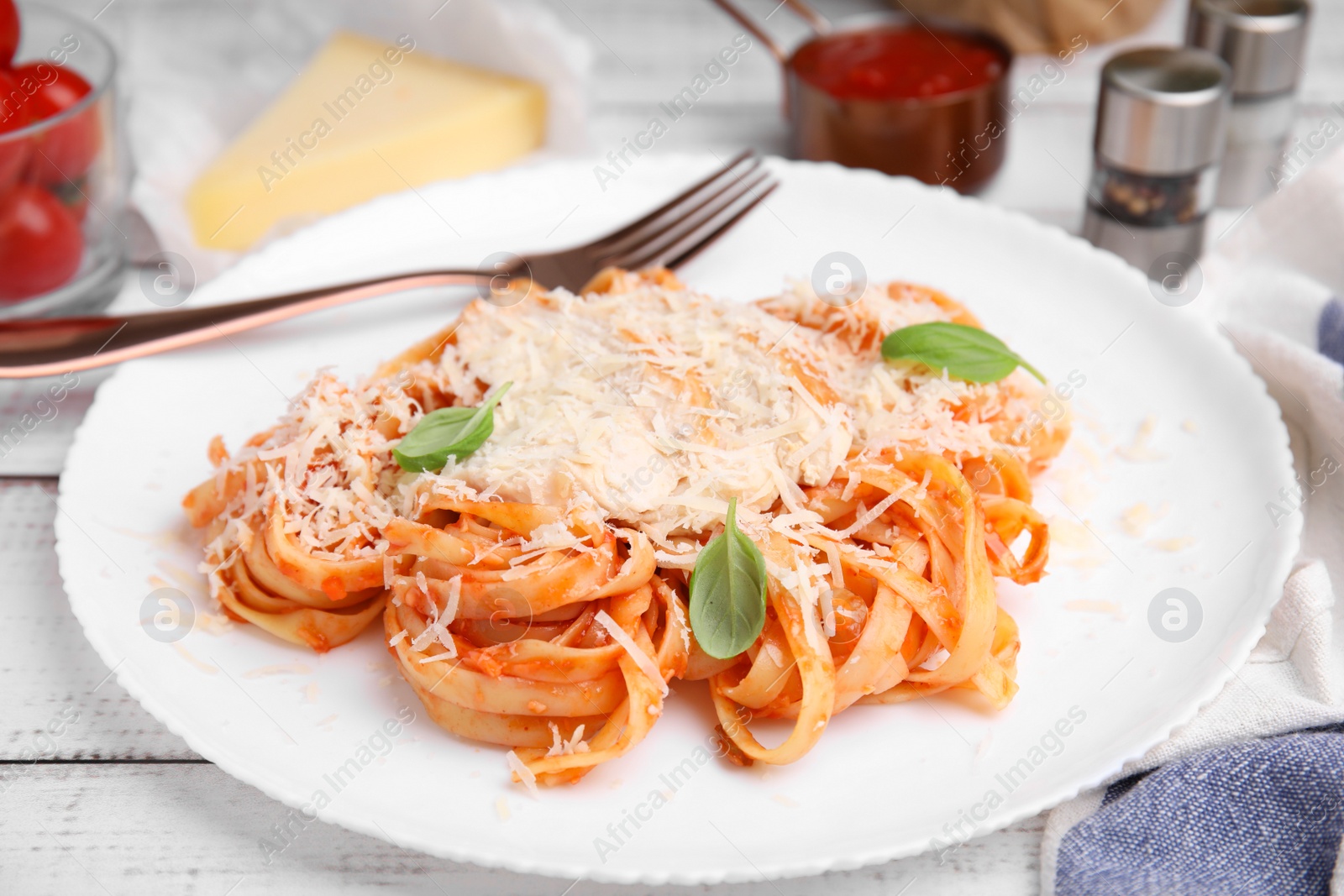 Photo of Delicious pasta with tomato sauce, chicken and parmesan cheese on white wooden table, closeup