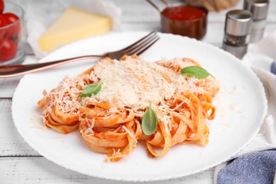 Delicious pasta with tomato sauce, chicken and parmesan cheese on white wooden table, closeup