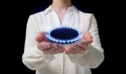 Closeup view of woman holding gas burner with blue flame on black background