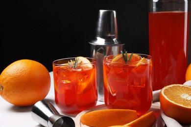 Photo of Aperol spritz cocktail, rosemary and orange slices on white table