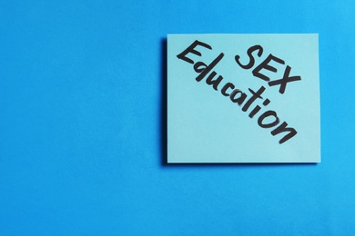 Photo of Note with phrase "SEX EDUCATION" on blue background, top view. Space for text