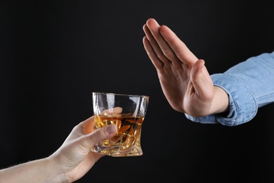 Photo of Alcohol addiction. Man refusing glass of whiskey on dark background, closeup