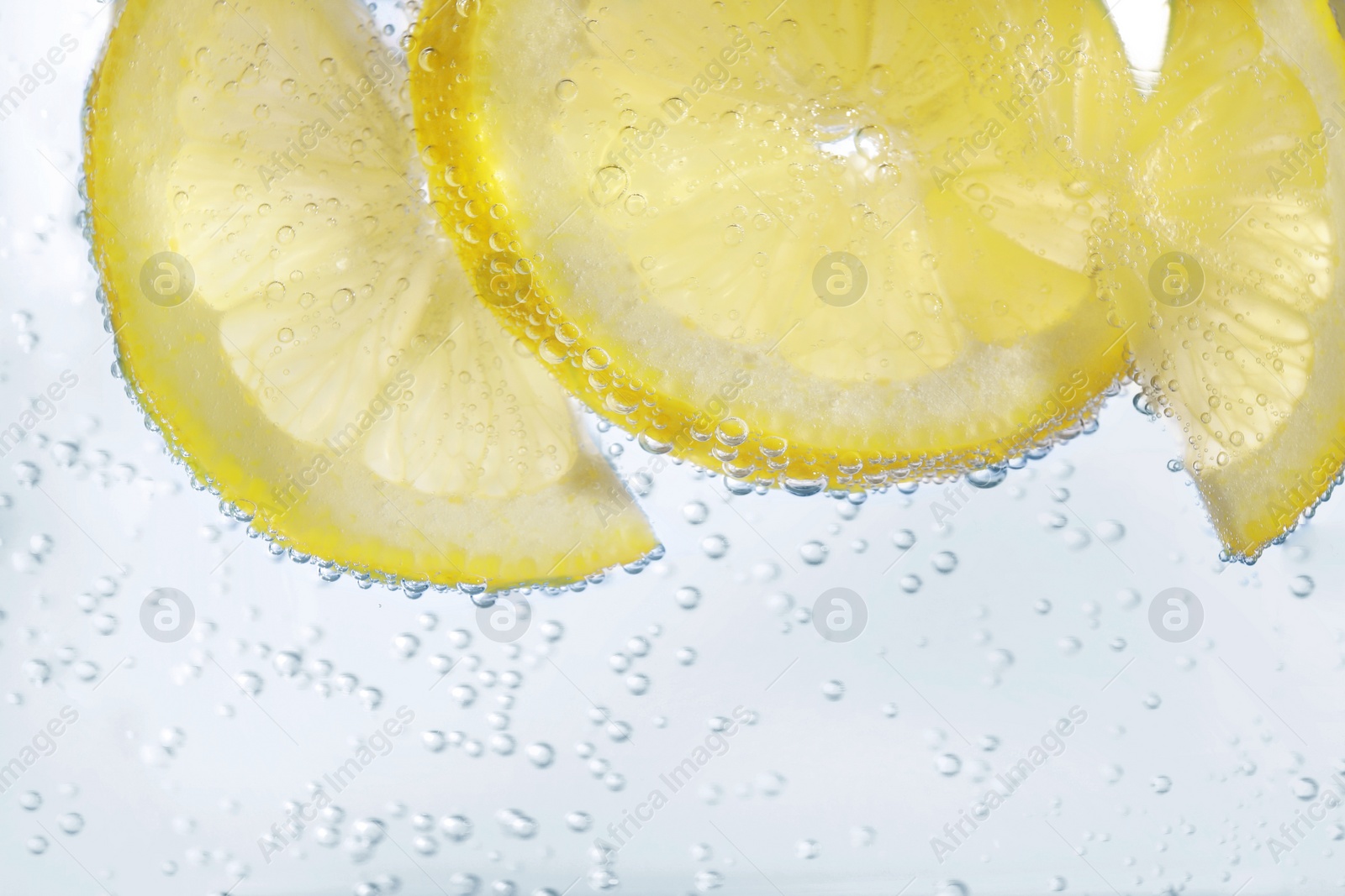 Photo of Juicy lemon slices in soda water, closeup