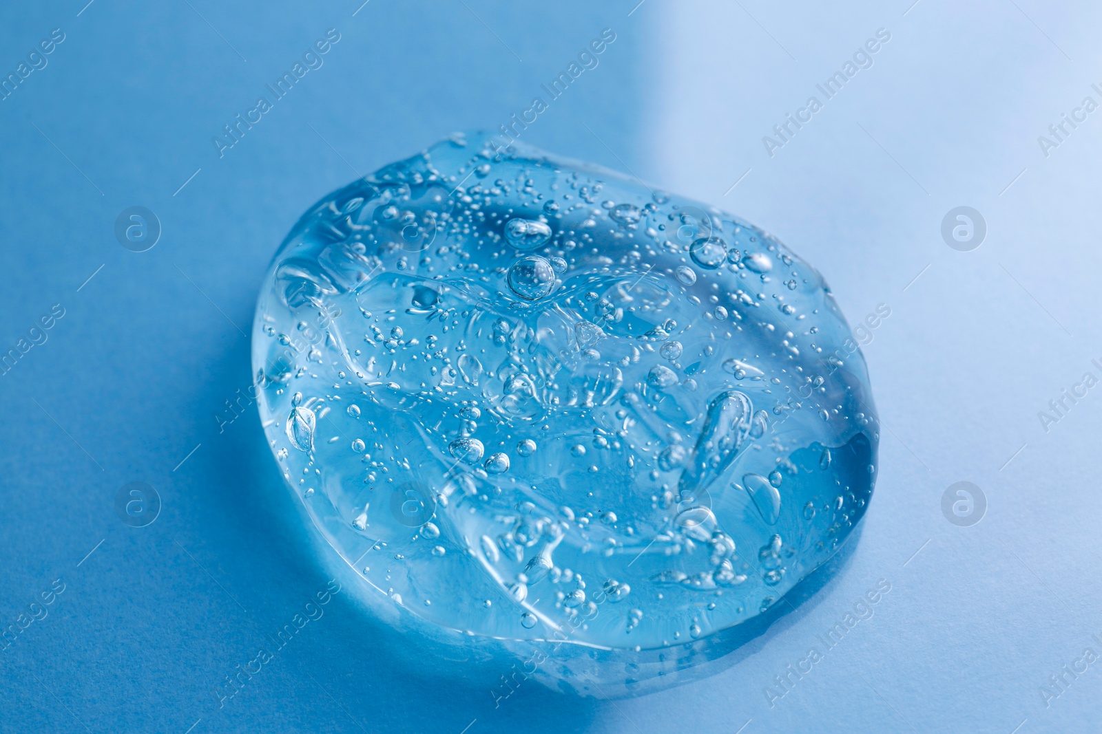 Photo of Sample of transparent shower gel on light blue background