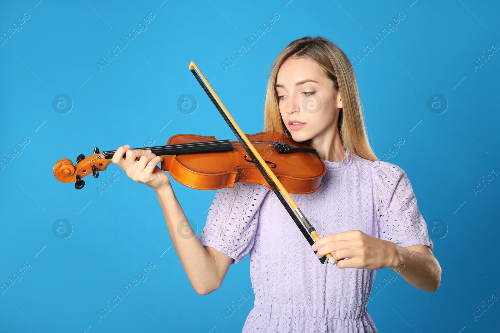 Photo of Beautiful woman playing violin on blue background