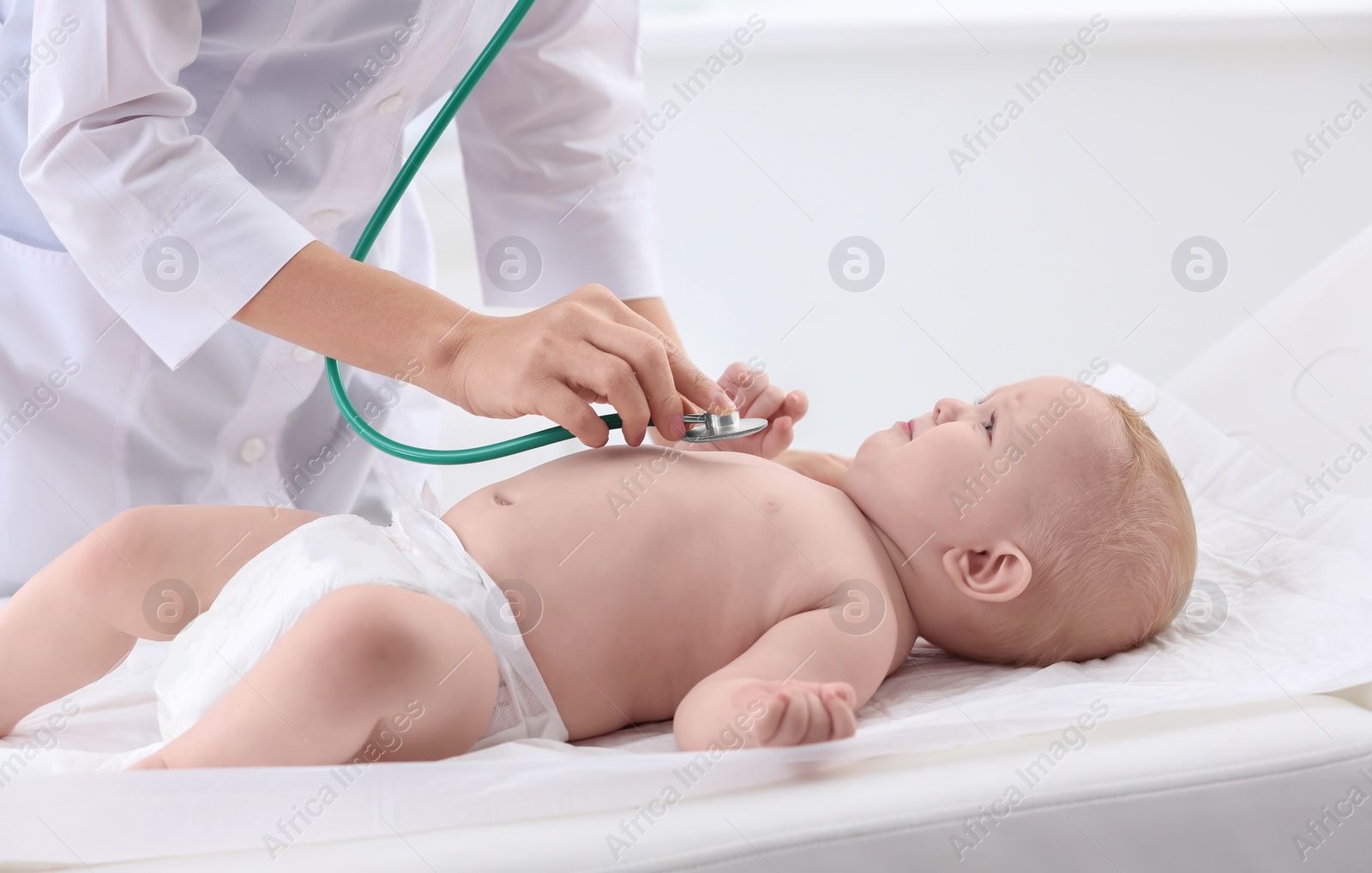 Photo of Children's doctor examining baby with stethoscope in hospital