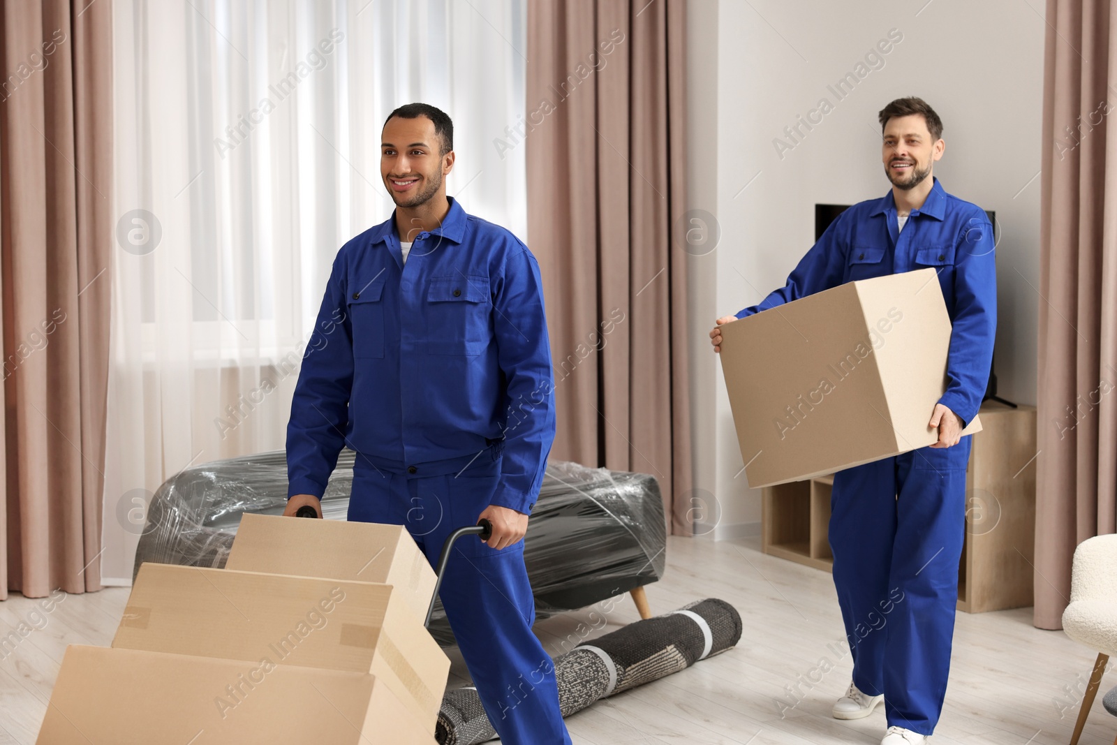 Photo of Male movers with cardboard boxes in new house