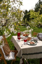 Photo of Stylish table setting with beautiful spring flowers, fruit drink and pie in garden