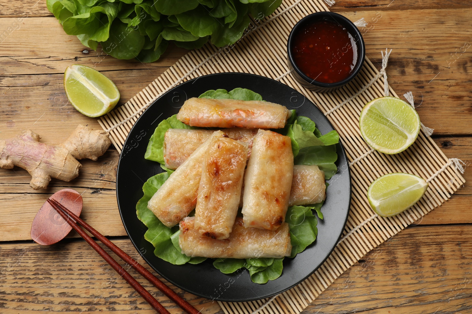 Photo of Tasty fried spring rolls served on wooden table, flat lay