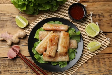 Photo of Tasty fried spring rolls served on wooden table, flat lay