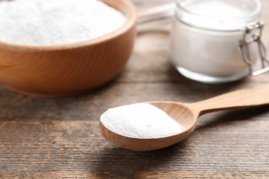 Spoon with baking soda on wooden table