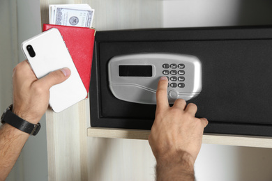 Man opening black steel safe with electronic lock at hotel, closeup