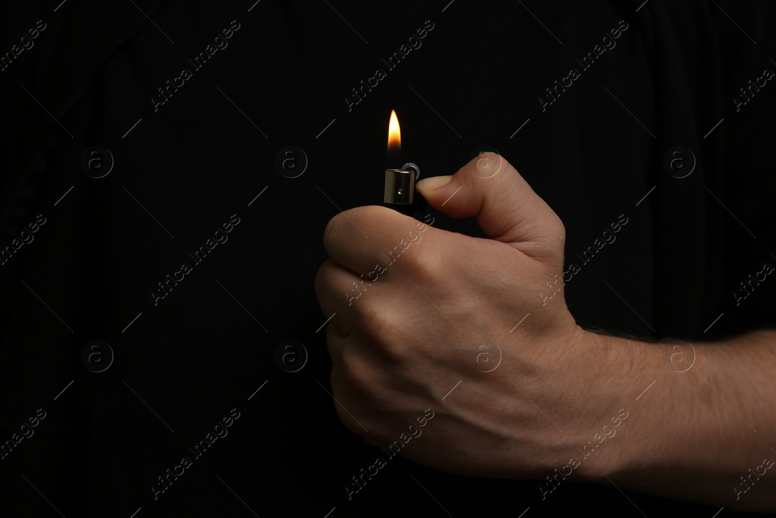 Photo of Man holding lighter on black background, closeup. Space for text