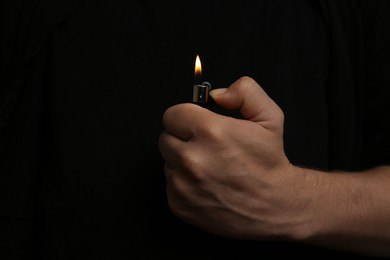 Photo of Man holding lighter on black background, closeup. Space for text